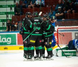 Hokejisti HK Olimpija med igro ob ogradi hokejskega igrišča.